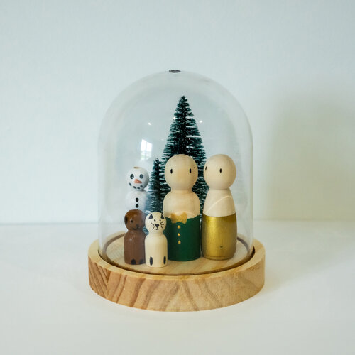 Poppetjesfamilie in kerstthema met kerstboom in een stolp